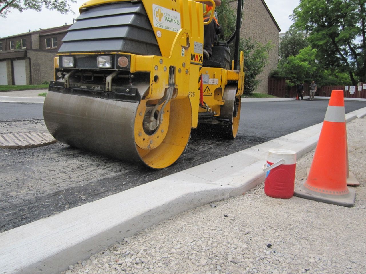 A yellow road roller is working on a street