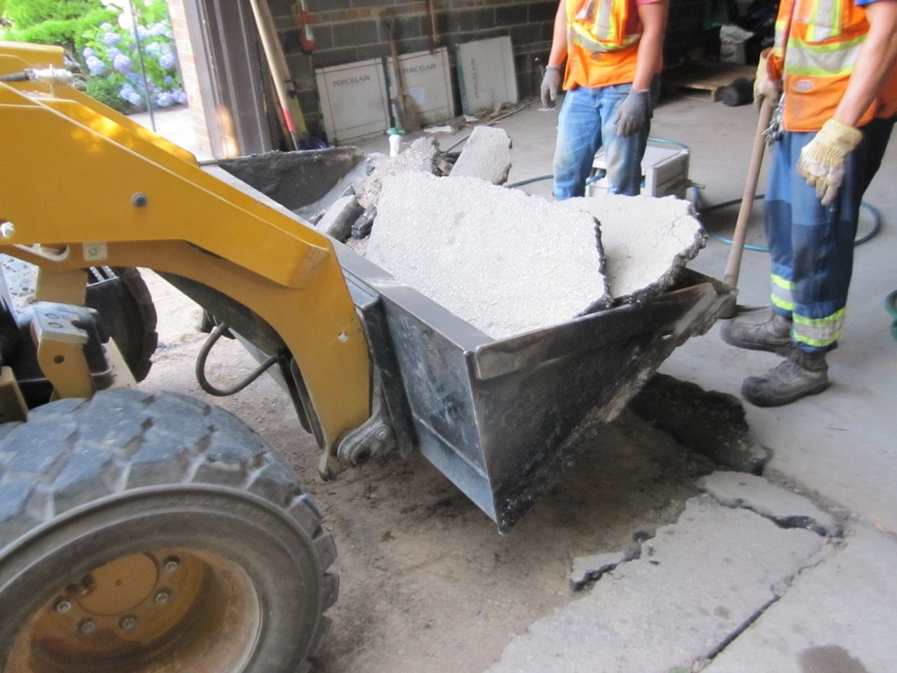 A yellow tractor is pushing a wheelbarrow full of rocks
