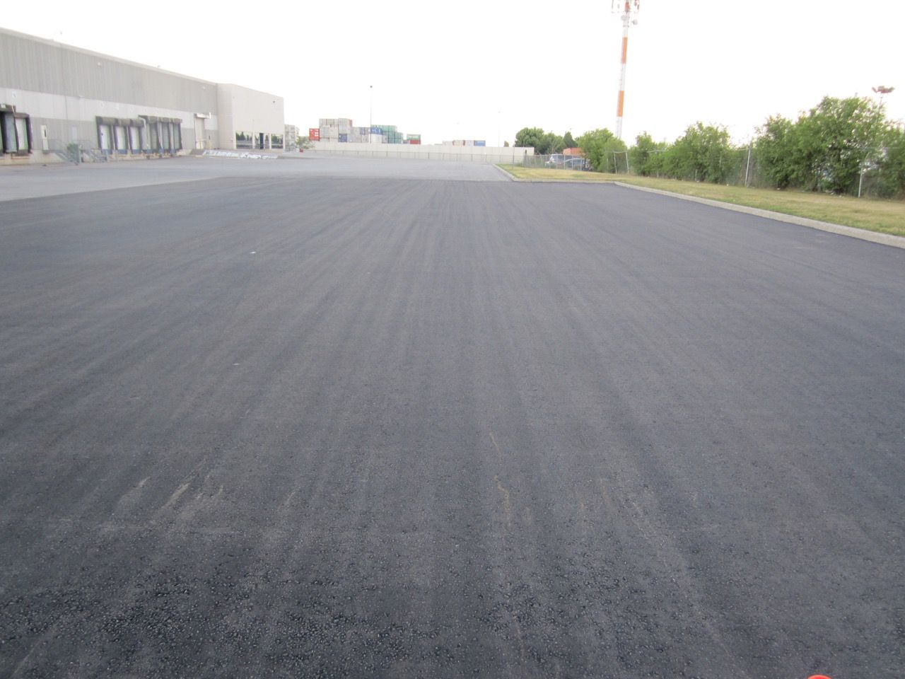 A large empty asphalt road with a building in the background.