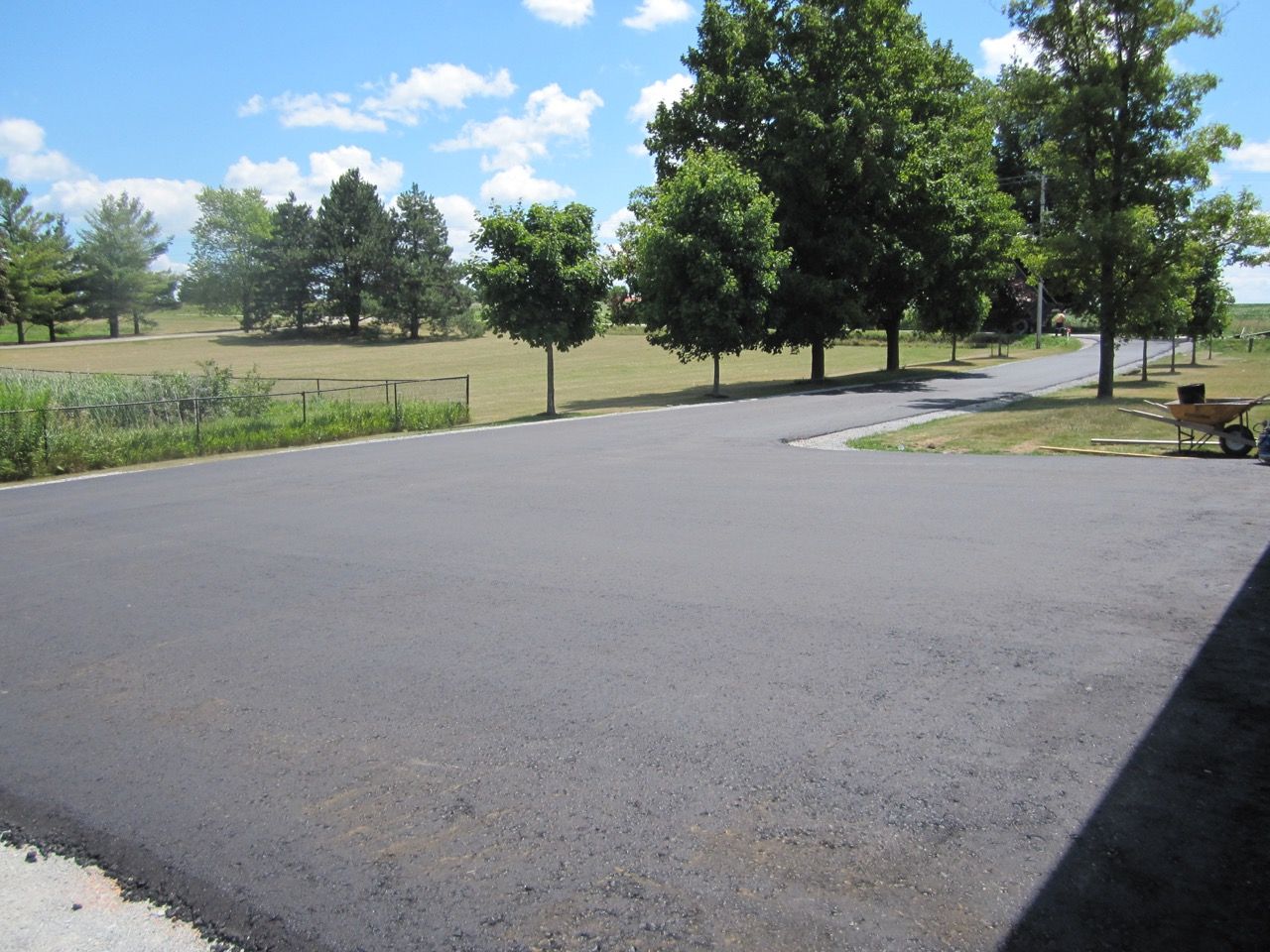 A large asphalt driveway with trees in the background