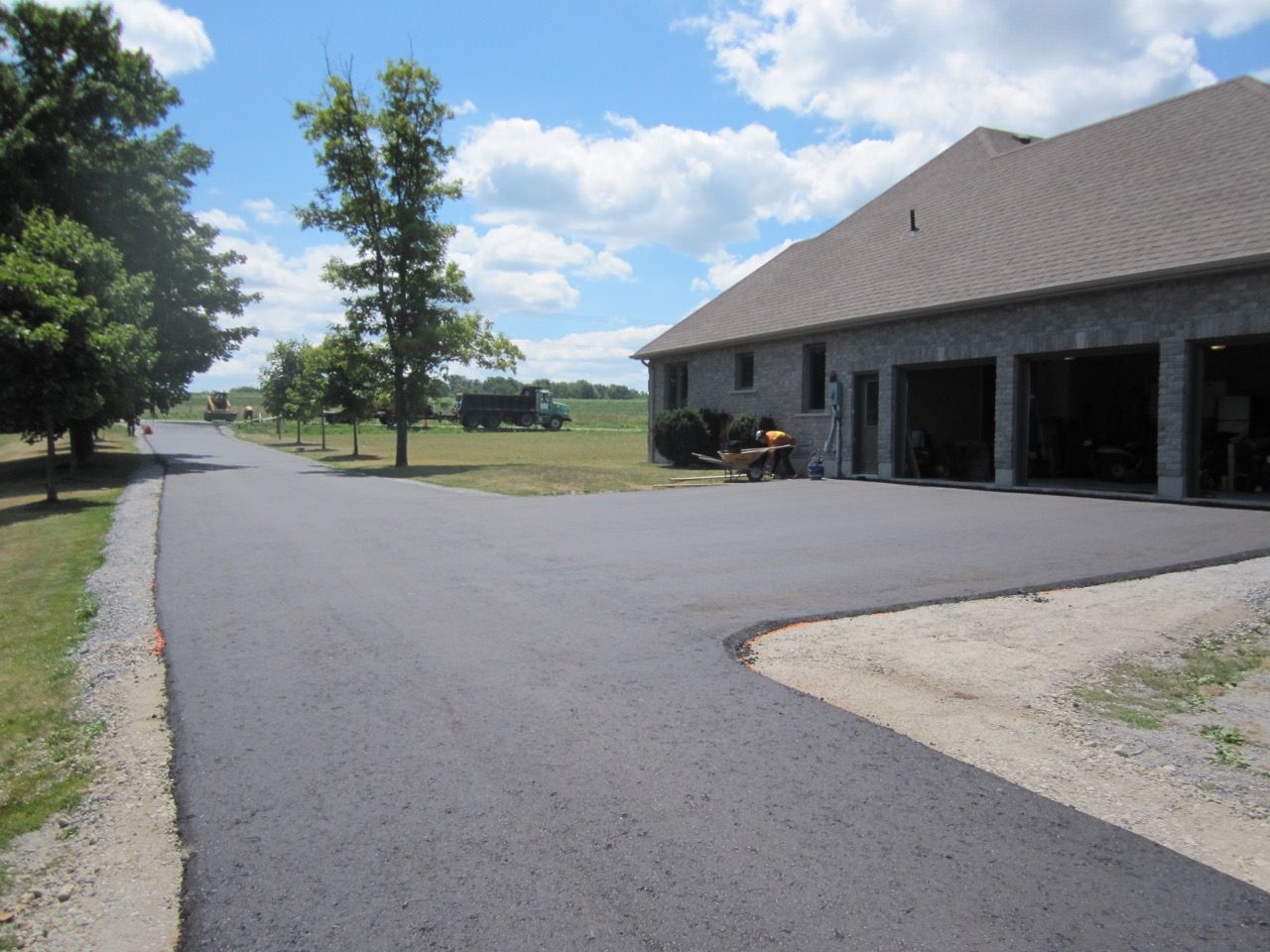 A driveway with a house in the background and trees on the side