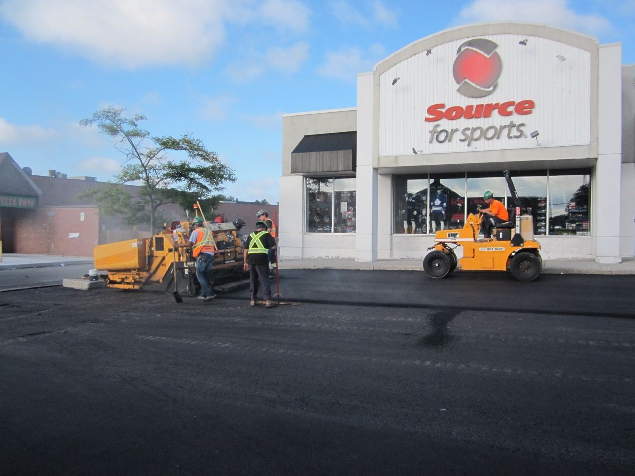 A group of people standing in front of a source for sports store