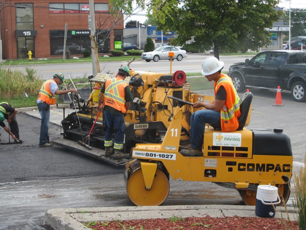 A group of construction workers are working on a compac road roller