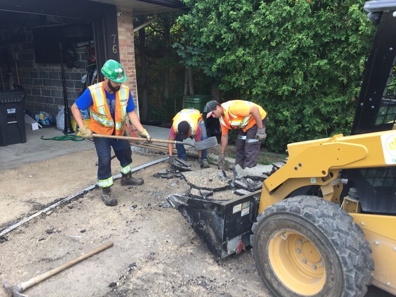 A group of construction workers are working on a driveway.