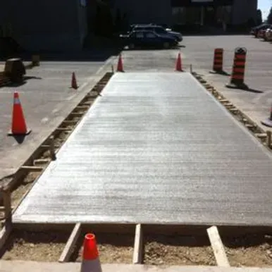 A concrete walkway is being built in a parking lot.