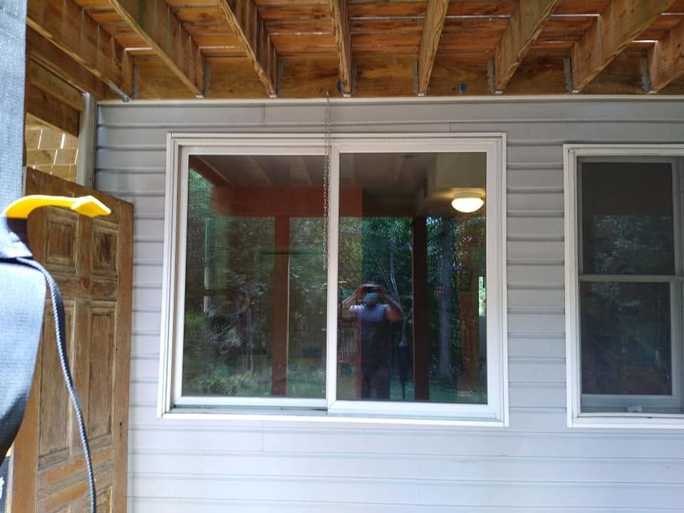 Exterior view of a house wall with two windows and a wooden porch ceiling