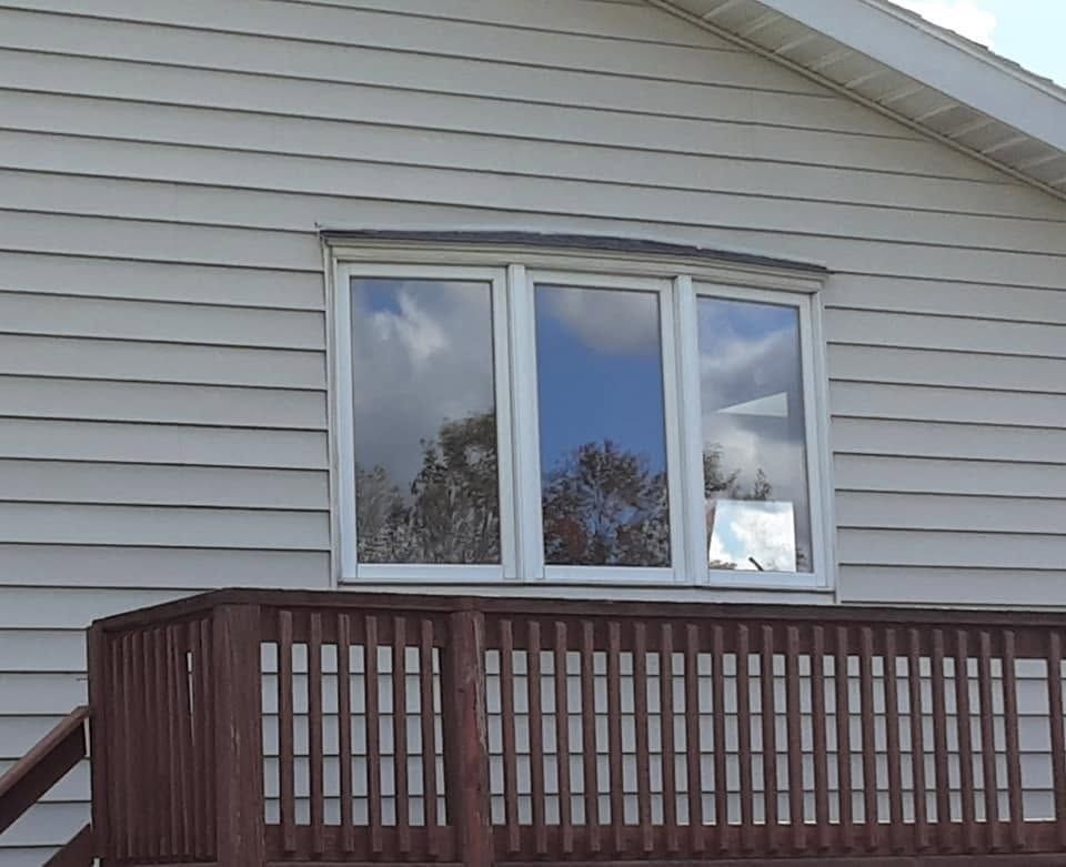 House exterior with gray siding, a window, and a brown wooden deck railing