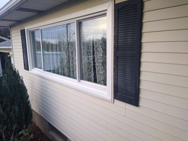 House exterior with white siding, large windows, and black shutters under the eaves