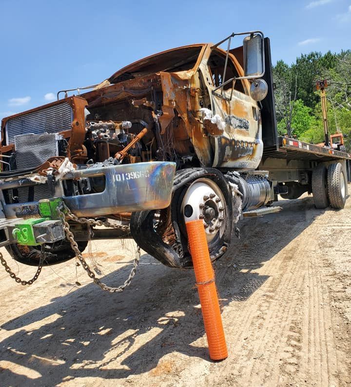 A truck that has been damaged is parked on a dirt road