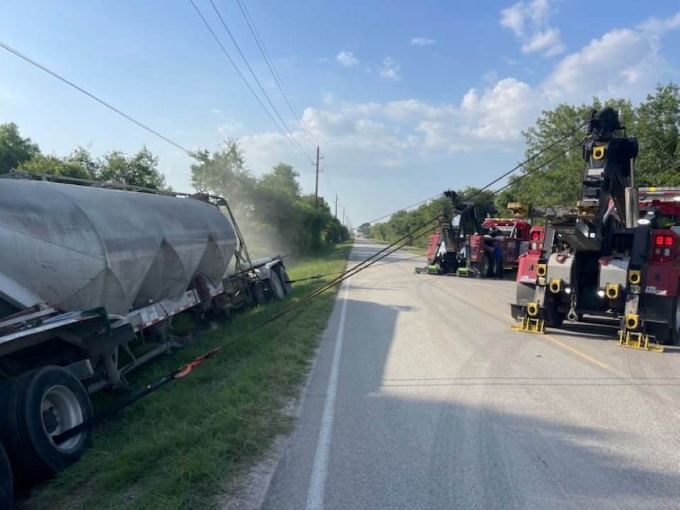 A truck is sitting on the side of the road next to a tow truck.