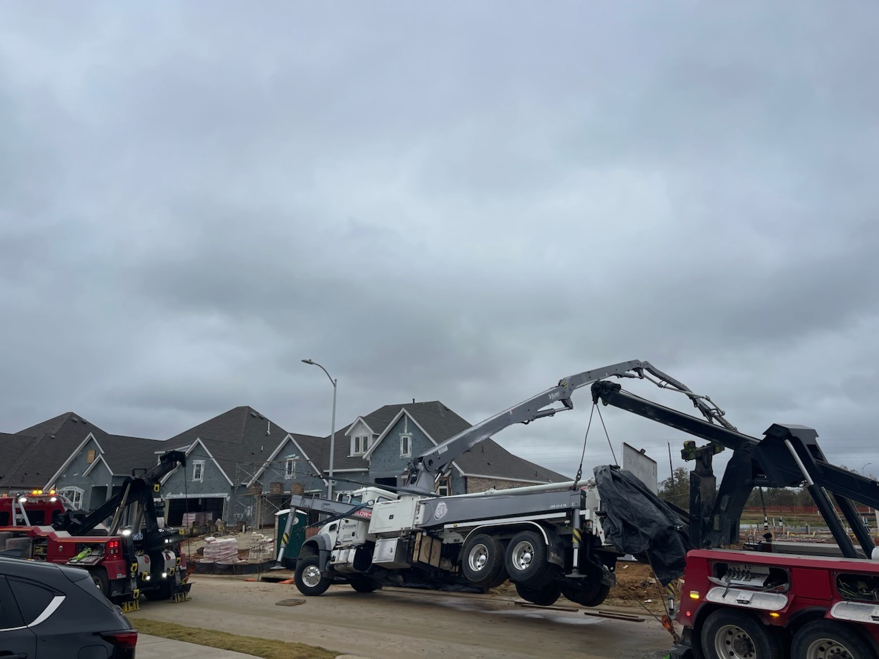 A truck is being towed down a street by a crane.