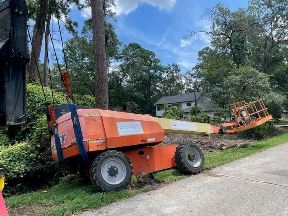 An orange lift is sitting on the side of the road next to a tree.
