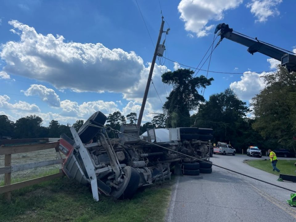 A truck is laying on its side on the side of the road.