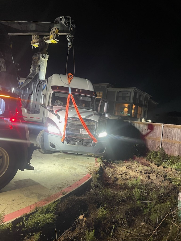 A truck is being towed by a tow truck at night.