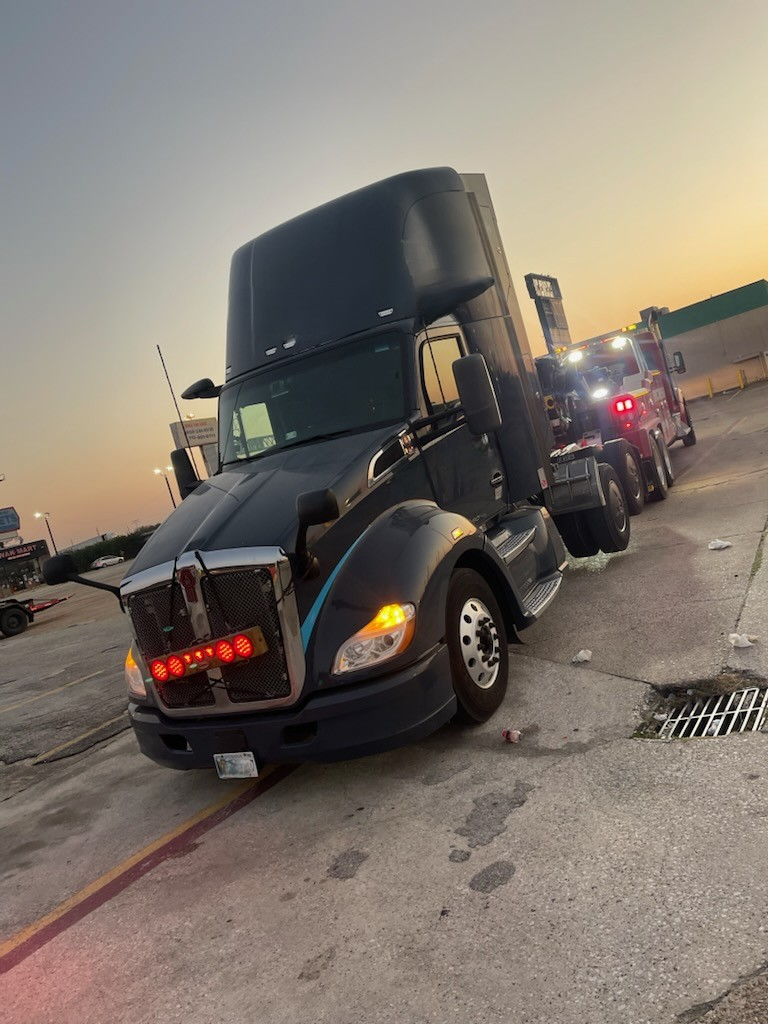 A black semi truck is parked in a parking lot.