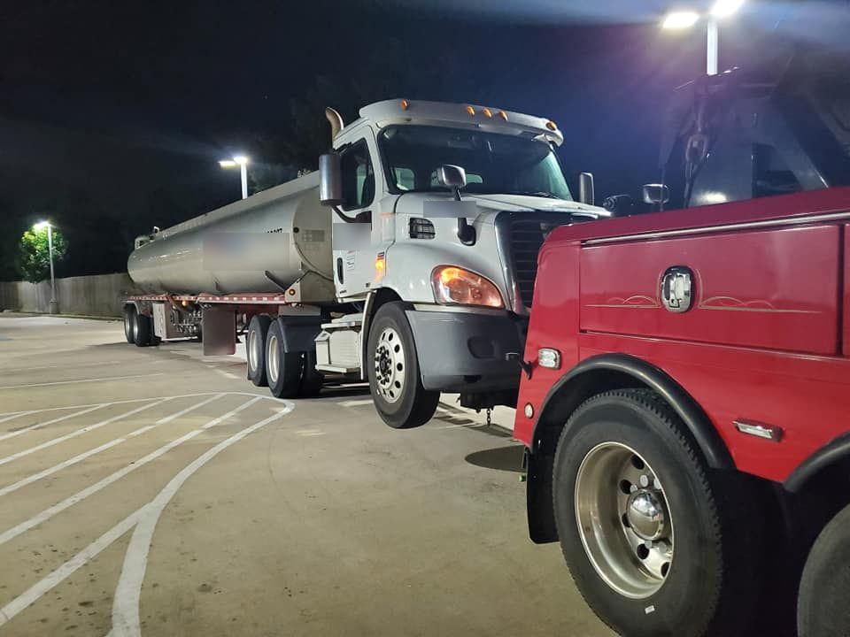 A car is being towed by a trailer in a parking lot.