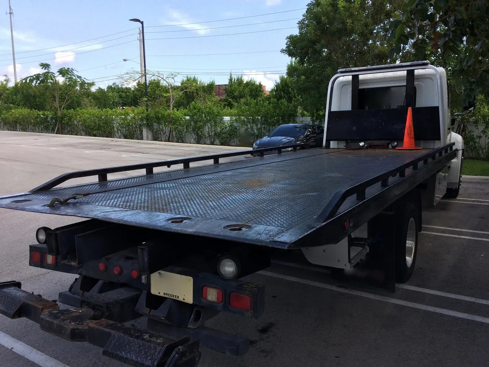A truck is carrying a roller on the back of it on a highway.