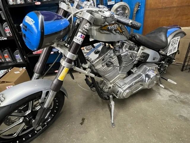 Silver custom motorcycle with blue accents, parked indoors.