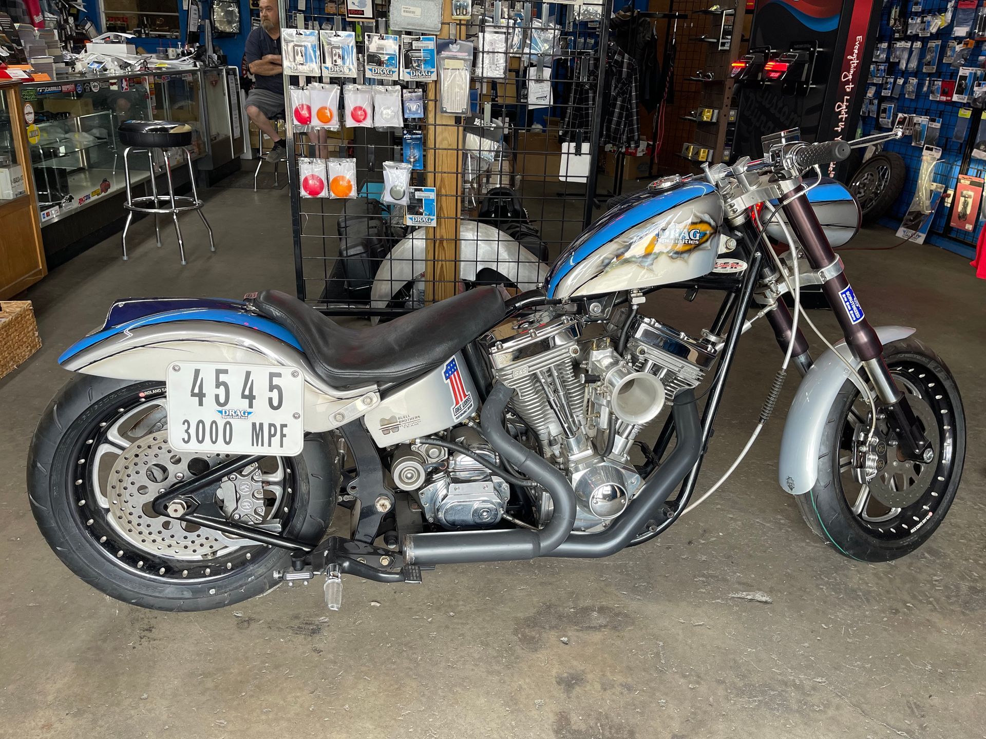 Silver custom motorcycle with blue accents, parked indoors.