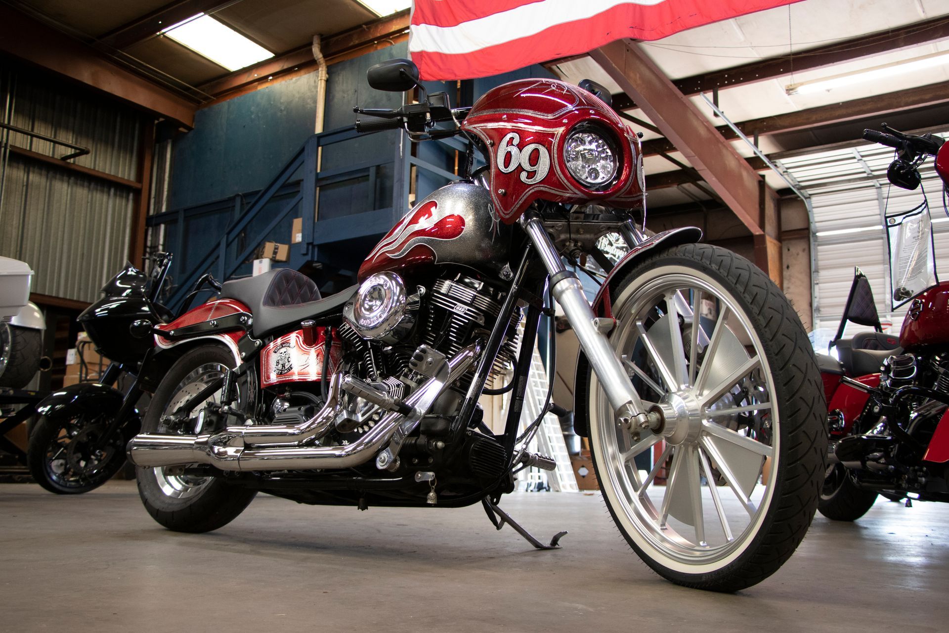 Two motorcycles parked in front of a Harley-Davidson shop with a metal awning on a sunny day.