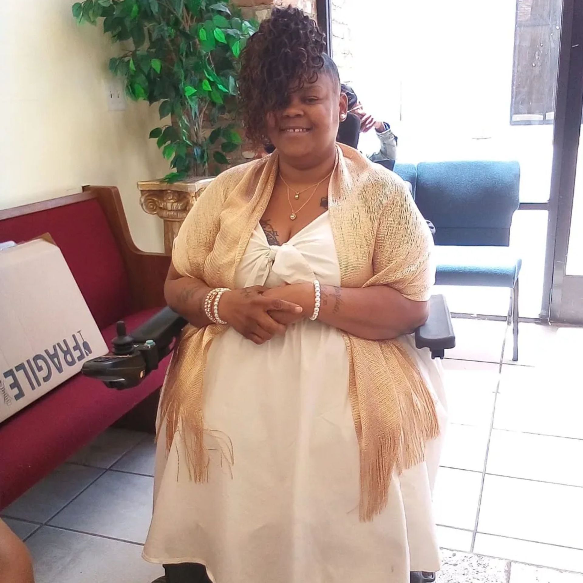 A woman in a white dress is standing in front of a fragile box