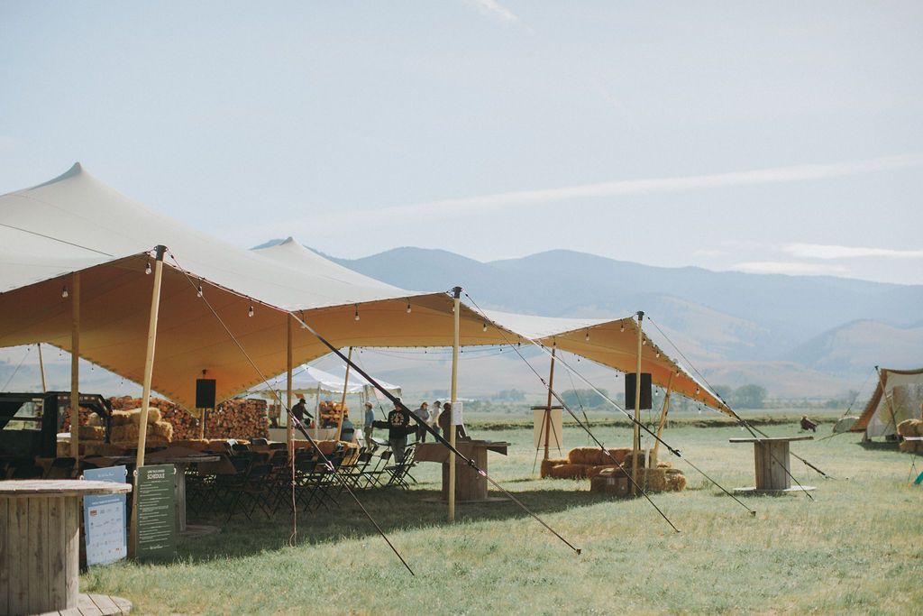 Open-air canopy tents in a desert camp with tables and mountains in the background