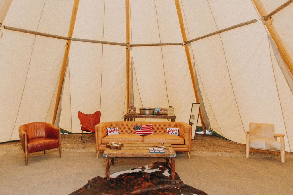 Cozy tent interior with a sofa, armchairs, rug, and small table in warm beige tones