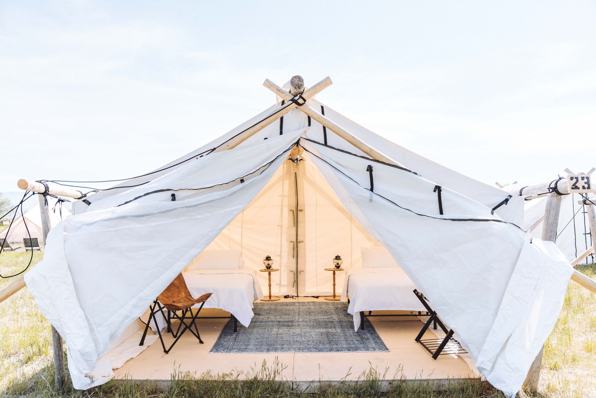 White canvas tent set up on a grassy field with chairs and a central aisle, viewed from the entrance.