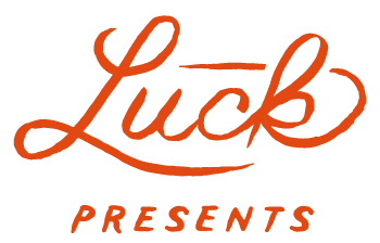 Orange script logo reading “Luck” with “PRESENTS” below on a white background