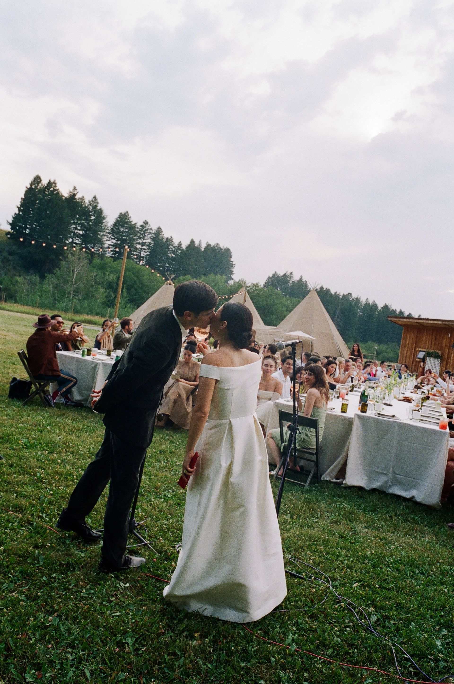 Bride and groom dancing outdoors at a wedding reception on a grassy lawn