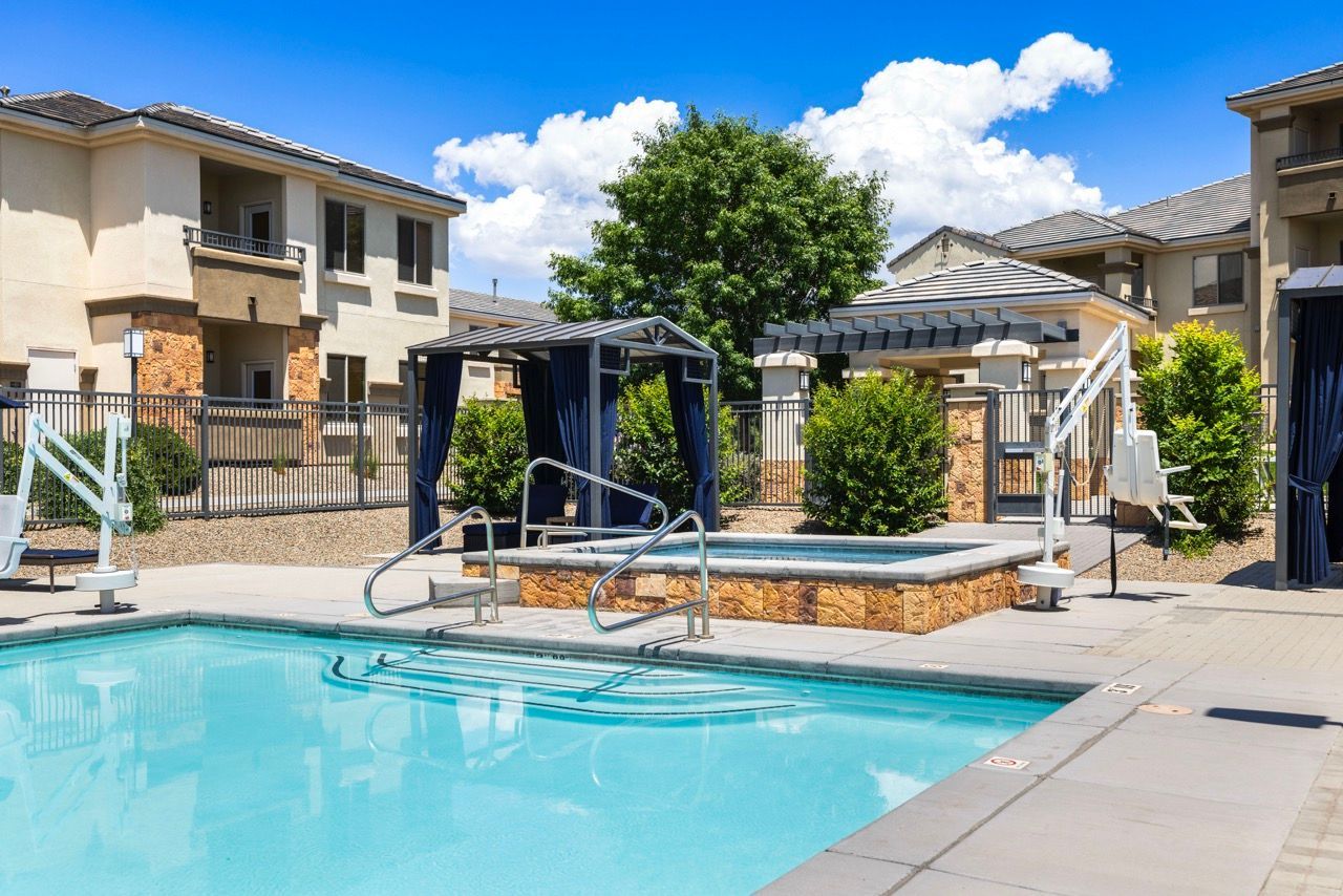 Outdoor community pool area with cabanas, a raised hot tub, and surrounding apartment buildings at Olympus Alameda, offering luxury apartments in Albuquerque.