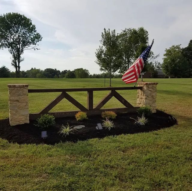 An american flag is flying in front of a wooden fence