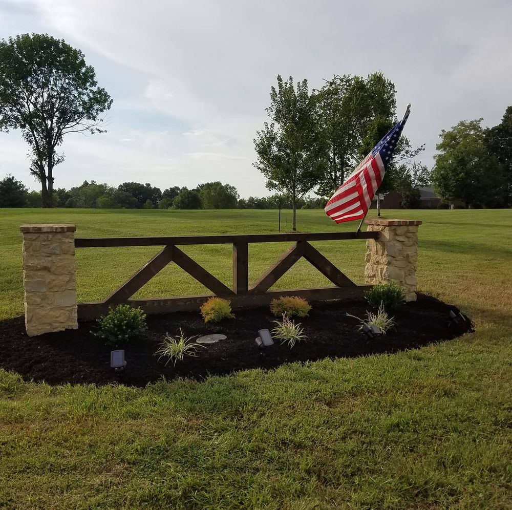 An american flag is flying in front of a wooden fence