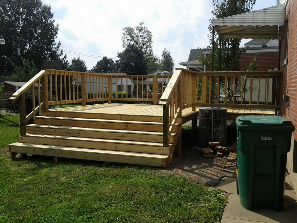 A wooden deck with stairs and a green trash can