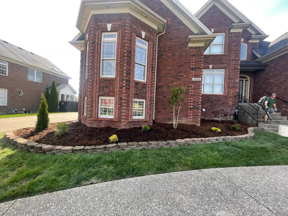 A large brick house with a lush green lawn in front of it.