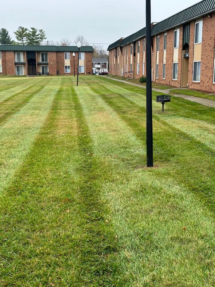 A lush green lawn is being mowed in front of a brick building.