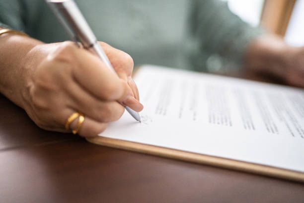 A person is writing on a piece of paper with a pen.