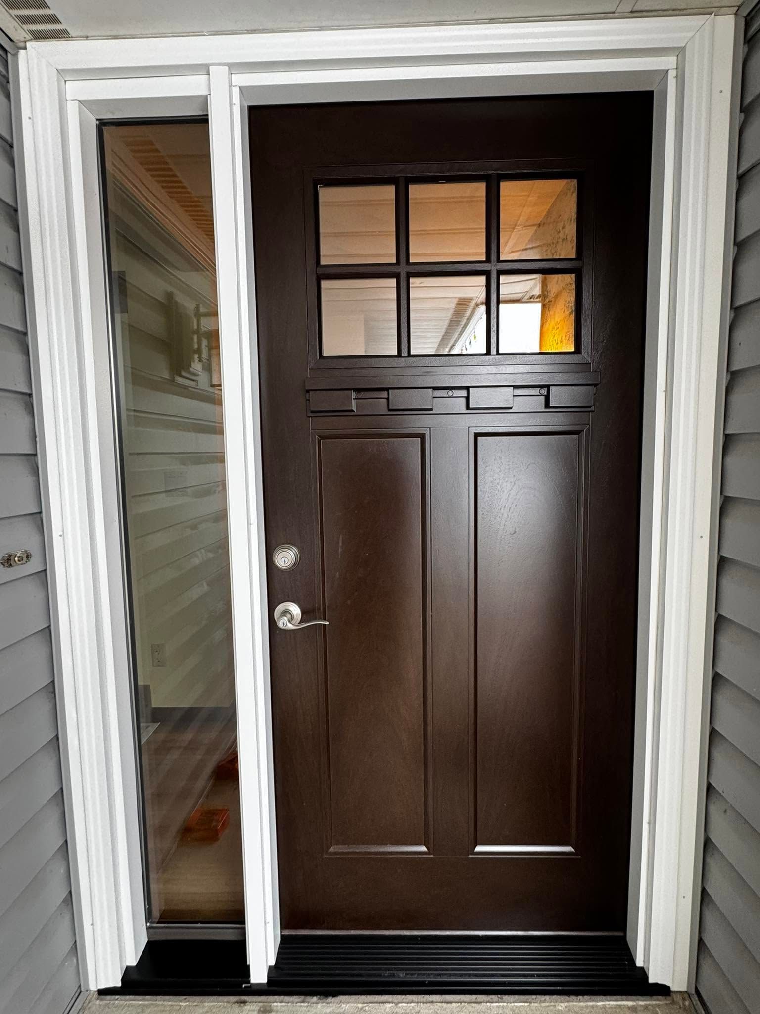 Dark brown front door with small window panes, framed by white trim at an entryway.