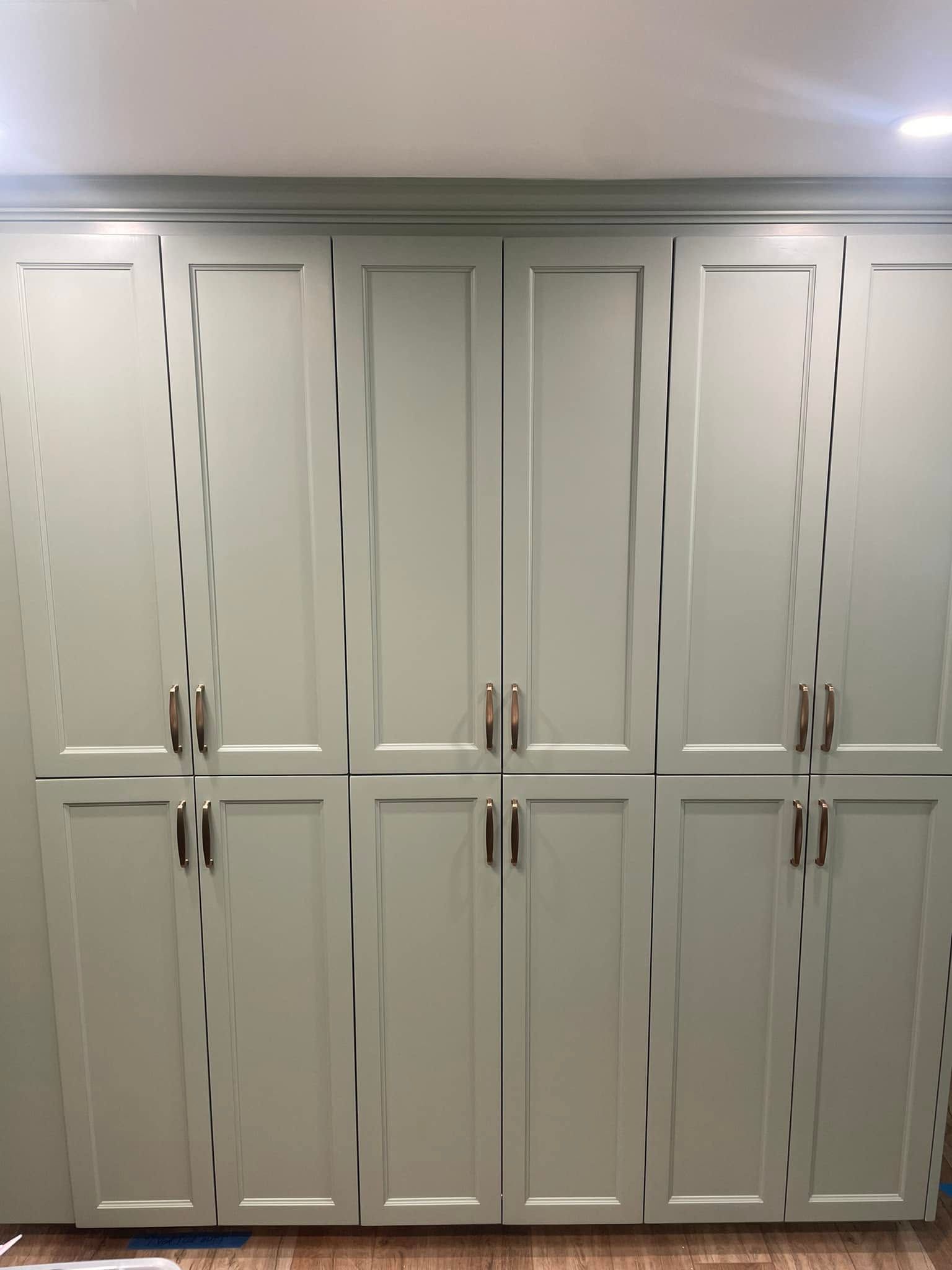 White built-in cabinet wall with multiple paneled doors and brass handles.