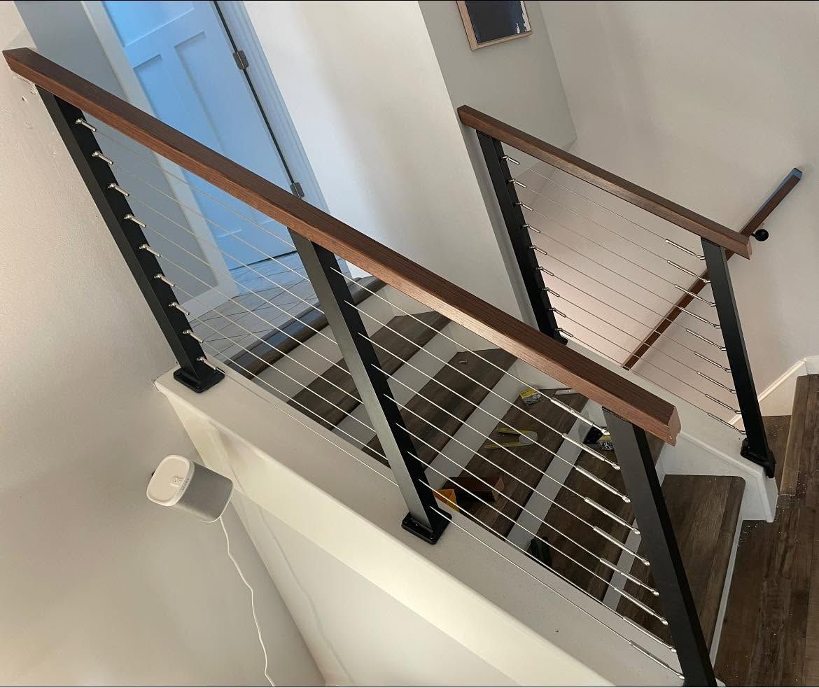 Indoor staircase with metal grating steps, black railings, and wooden handrails.