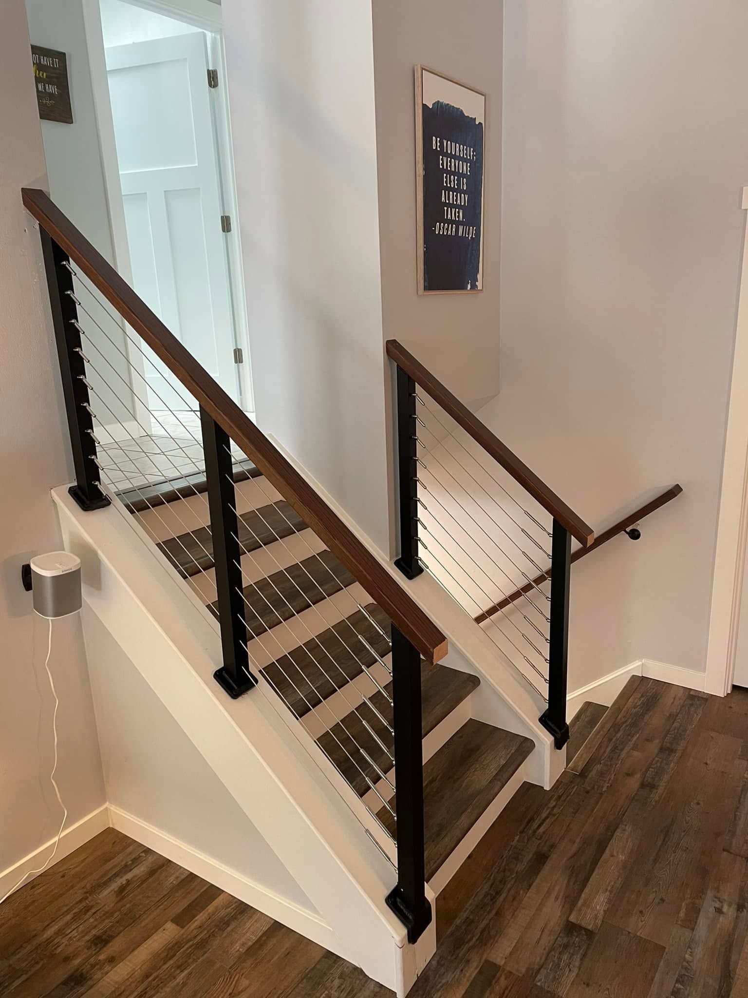 Interior staircase with dark wood steps, black railings, and white walls in a modern home.