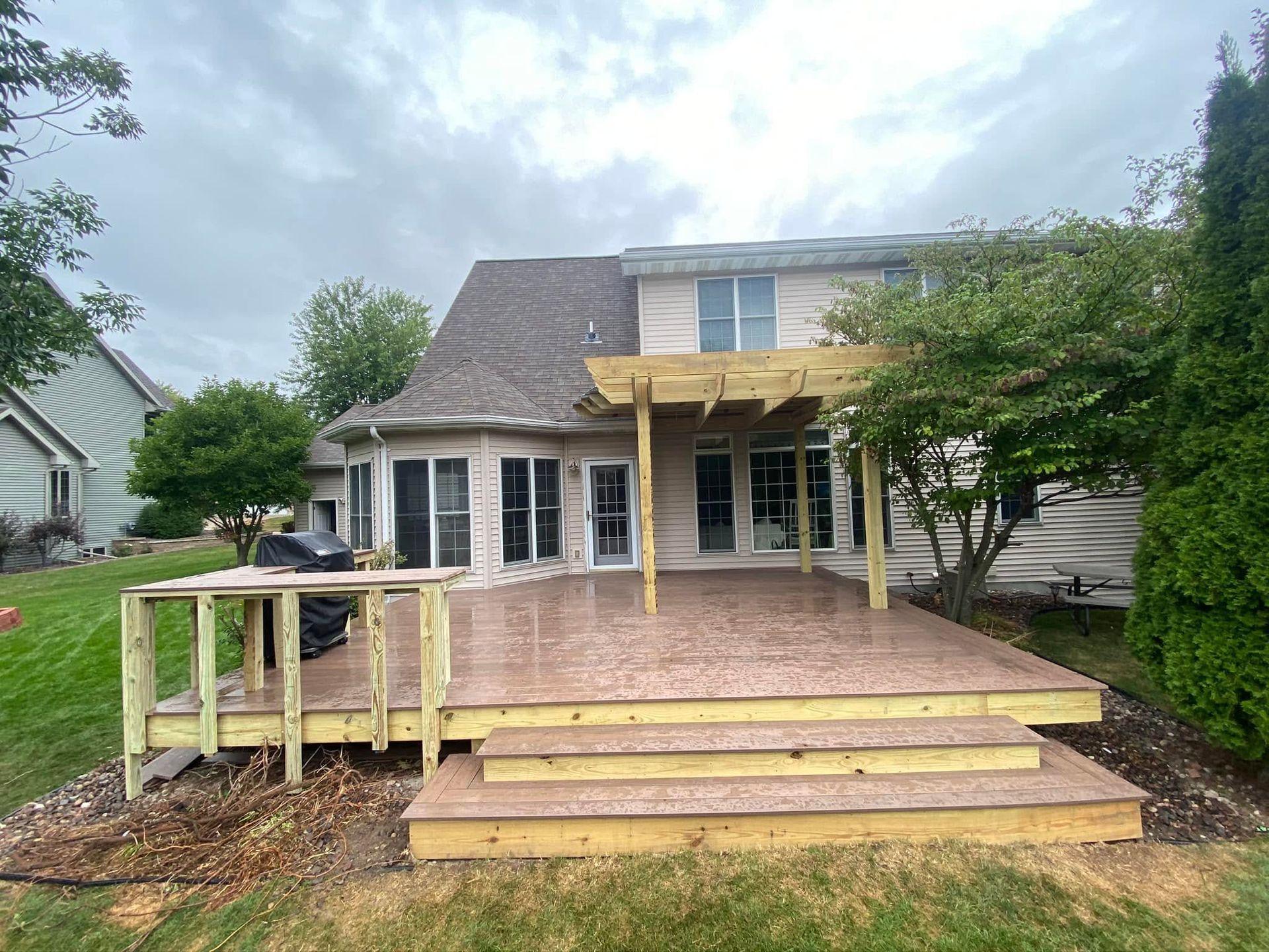 Back deck under construction on a suburban house, with exposed wood framing and steps leading down to the yard
