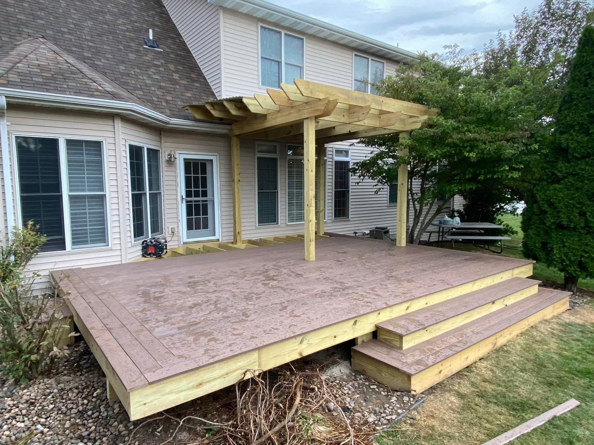 Backyard wooden deck with stairs and pergola attached to a house