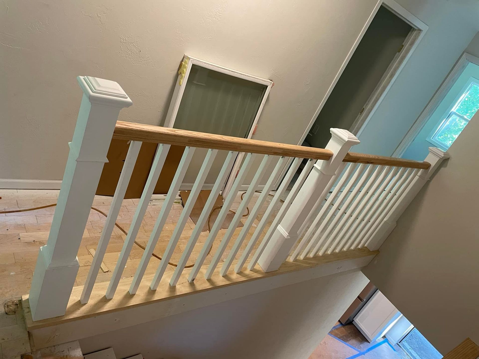 Stair landing with white railing and wood handrail inside a home, viewed from above.