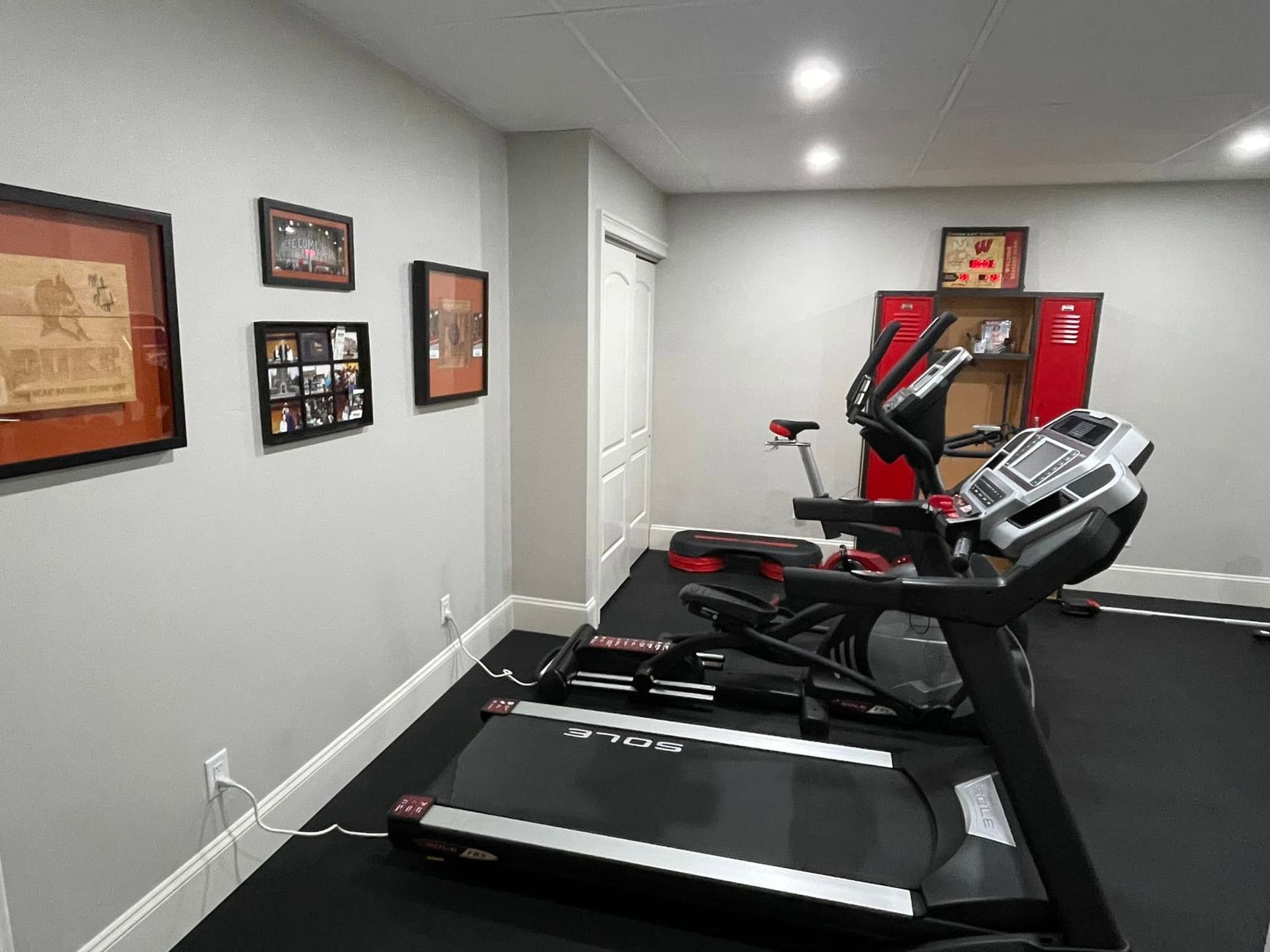 Basement home gym with treadmills, framed wall art, and recessed ceiling lights