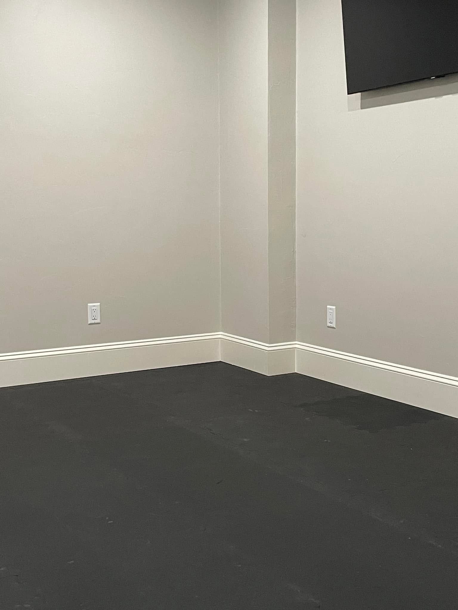 Empty gray room with black carpet and white chair rail molding