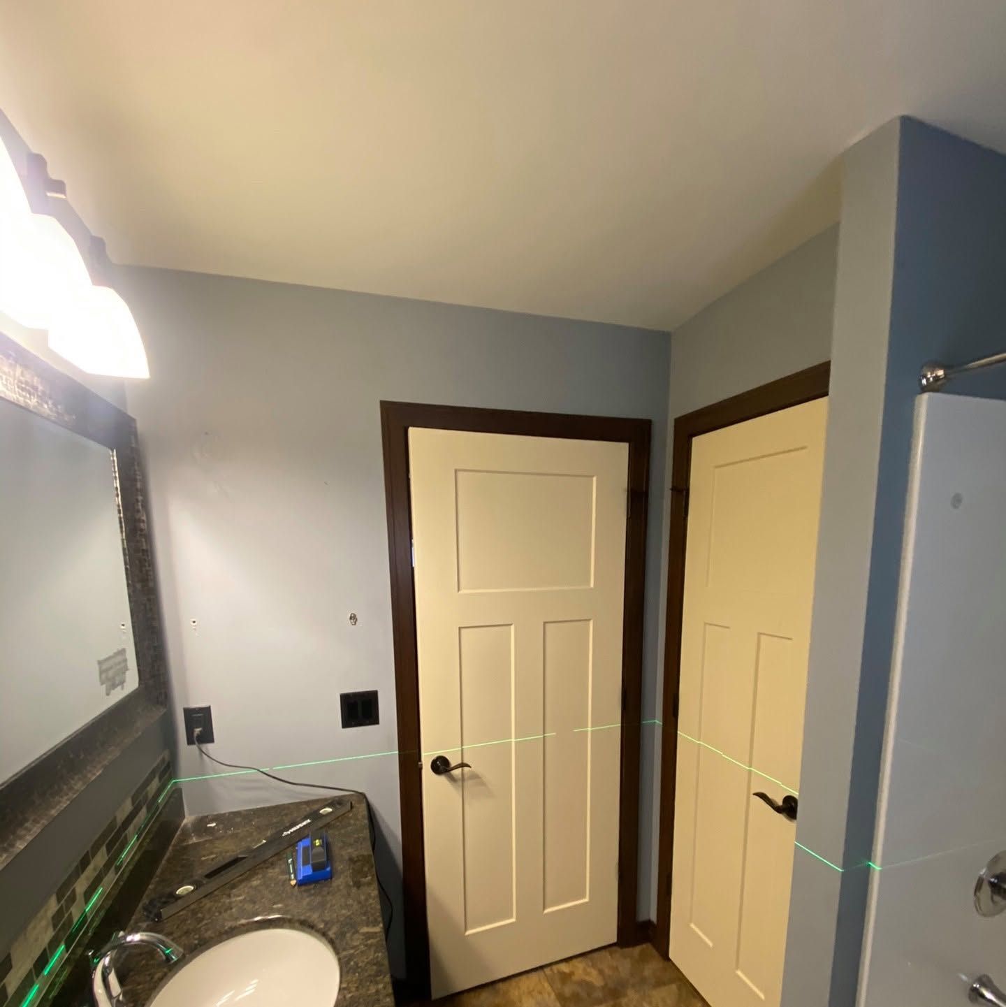 Bathroom vanity and mirror beside two cream doors in a blue-gray room