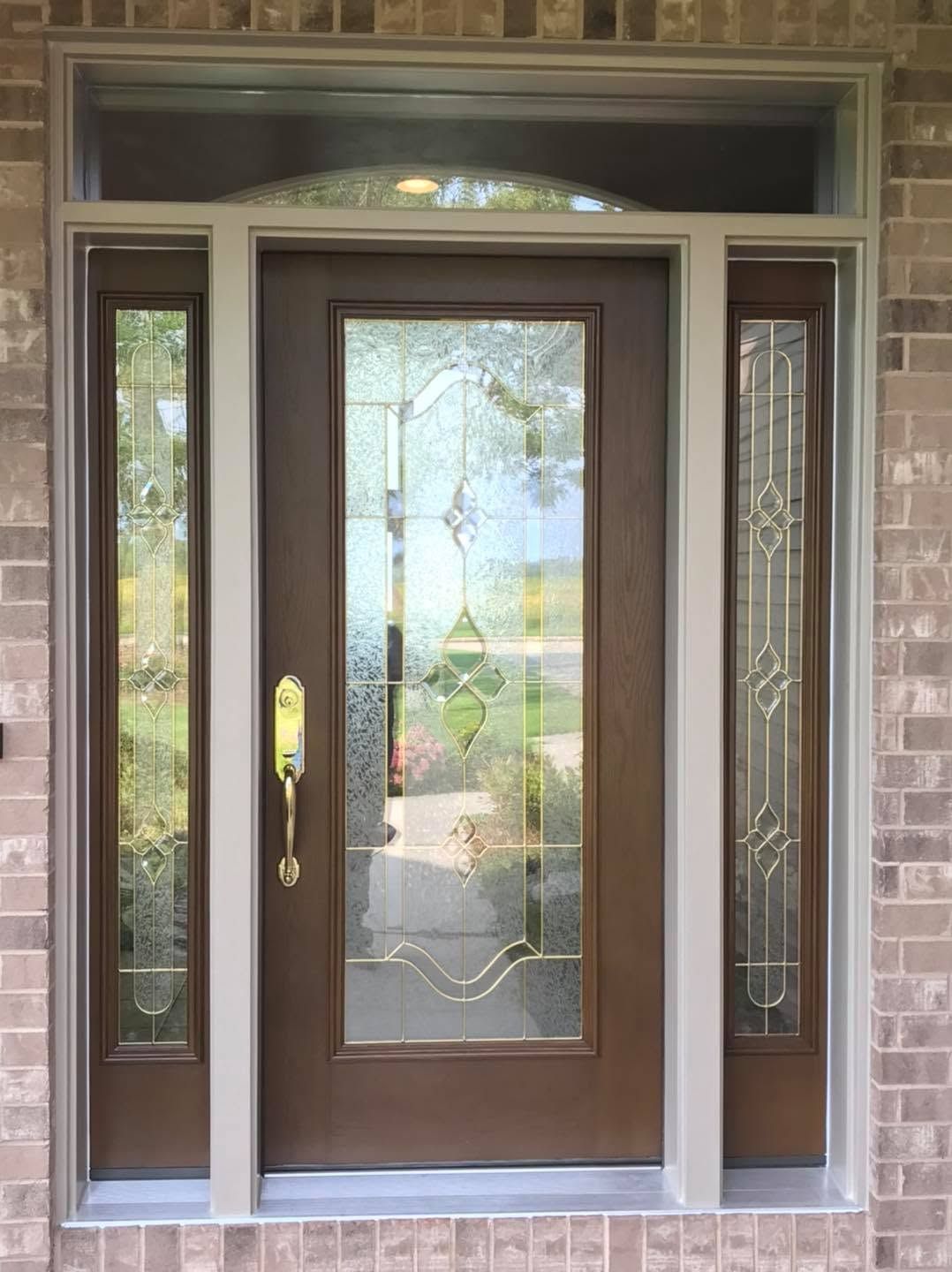 Front entry with a brown door, glass sidelights, and a decorative transom window set in brick.