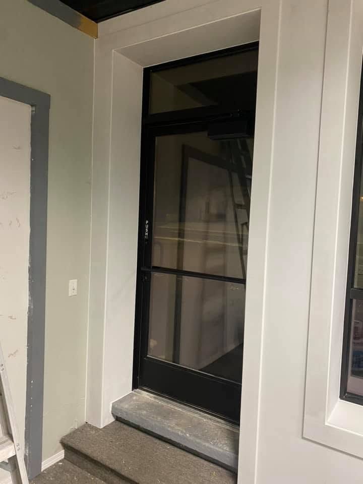 Black screen door in a white door frame, viewed from a stair landing indoors.