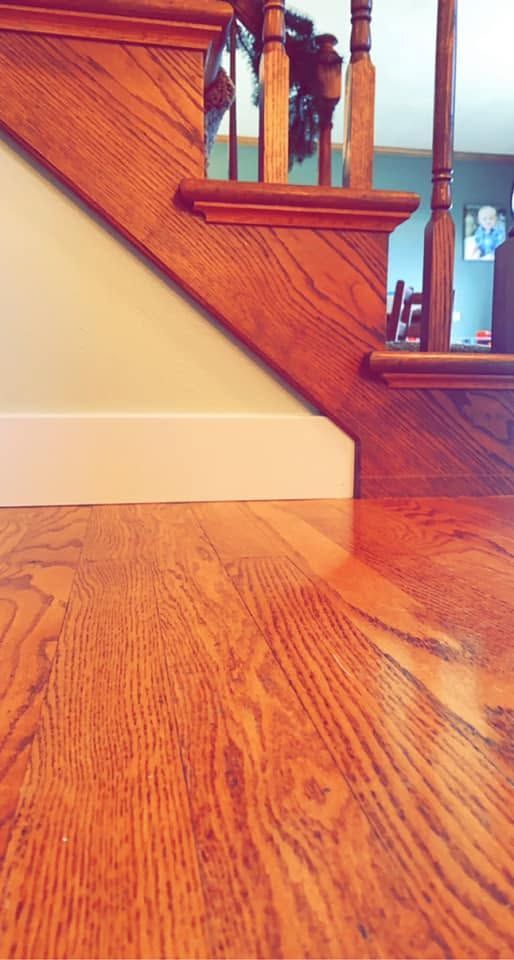 Wooden staircase and polished hardwood floor in a warmly lit interior.